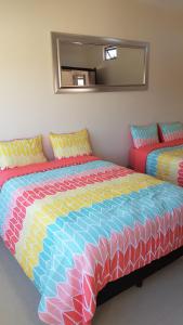 een slaapkamer met een groot bed en een kleurrijk dekbed bij Suites Lagunas in Colima
