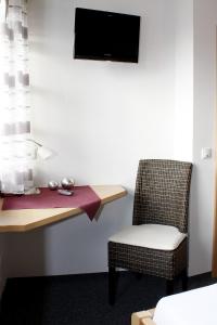Cette chambre comprend un bureau, une chaise et une télévision. dans l'établissement Landgasthaus Badischer Hof, à Großrinderfeld