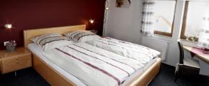a bedroom with a bed and a desk and a window at Landgasthaus Badischer Hof in Großrinderfeld +1 photo