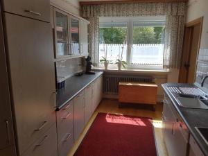 eine Küche mit weißen Schränken und einem roten Teppich in der Unterkunft Beim Dobis in Lutzingen