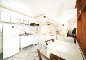 eine Küche mit weißen Schränken und einem weißen Tisch in der Unterkunft Latte&Miele in Ragusa
