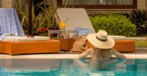 a woman in a straw hat sitting in a swimming pool at Olympion Sunset Halkidiki in Fourka