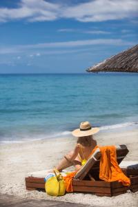 a woman in a hat sitting on a beach at Olympion Sunset Halkidiki in Fourka