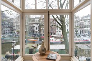 ein großes Fenster mit Blick auf einen Fluss und Boote in der Unterkunft A B&B Amsterdam in Amsterdam
