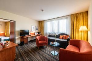 a living room with a couch and chairs in a hotel room at Mercure Hotel am Messeplatz Offenburg in Offenburg