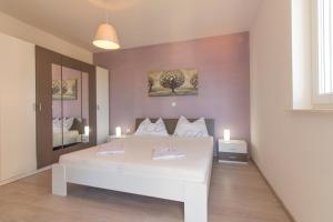 a bedroom with a white bed with two candles on it at Villa Sunset in Rogoznica +29 photos