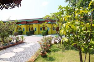 um edifício amarelo com um pátio com árvores e plantas em The Moonlight Resort em Ban Chang