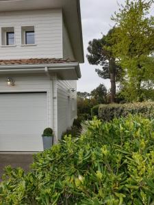 une maison blanche avec une porte de garage blanche dans l'établissement La Maison Blanche, à Andernos-les-Bains