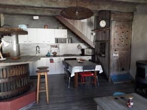 una cocina con armarios blancos y una mesa con sillas. en Le Pressoir, en Saint-Julien-de-Coppel