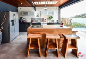a kitchen with a large wooden island with stools at Villa Fleur d'O in Le Robert