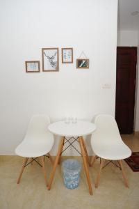 a white table and four white chairs in a room at Ruby Lakeview homestay in Hanoi
