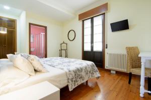 Schlafzimmer mit einem Bett, einem TV und einem Fenster in der Unterkunft Casa do Marqués in Baiona
