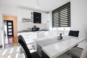 Una cocina blanca con una mesa de comedor y sillas. en White Spacious Apartment, en Sibiu