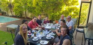 un grupo de personas sentadas en una mesa en Riversong Guest House en Ciudad del Cabo