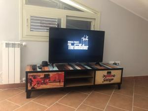telewizor z płaskim ekranem siedzący na stojaku telewizyjnym w obiekcie The Godfather Apartment w mieście Fiumefreddo di Sicilia