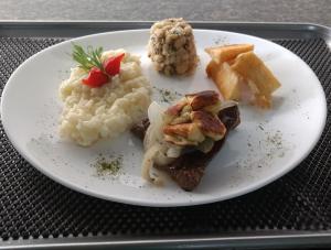 un plato de comida con puré de patatas y carne en Raru's Motel Ponta Negra (Adult Only) en Natal