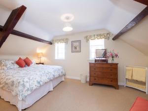 a bedroom with a bed and a dresser with a television at Holiday Home The Carriage House by Interhome in Worton