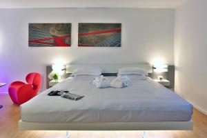 a bedroom with a large white bed with a red chair at Urban Hotel Design in Trieste
