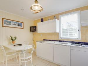 a kitchen with white cabinets and a table with chairs at Studio Les Genêts by Interhome in La Richardais