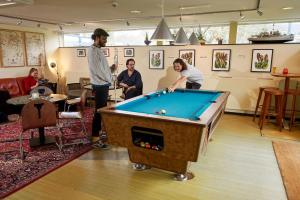 a group of people playing pool in a room at Pension Homeland in Amsterdam