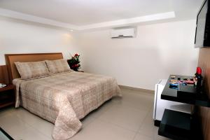a hotel room with a bed and a television at Raru's Motel Ponta Negra (Adult Only) in Natal
