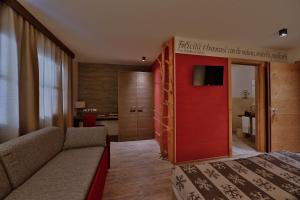 Habitación de hotel con sofá y puerta roja en Chalet Tovel - Mountain Lake en Tuenno