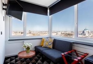 a living room with a couch in front of windows at AZIMUT Hotel Saint-Petersburg in Saint Petersburg