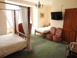 a bedroom with two beds and a tv and a chair at Môr Wyn Guest House in Barmouth