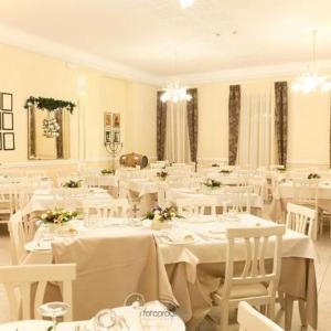 jadalnia z białymi stołami i białymi krzesłami w obiekcie Albergo Roma w mieście Borgo Val di Taro