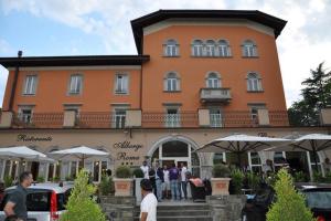 ein großes orangenes Gebäude mit Leuten, die draußen stehen in der Unterkunft Albergo Roma in Borgo Val di Taro