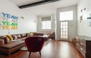 een woonkamer met een bruine bank en een rode stoel bij The South Kensington Mews - Lovely 5BDR Home in Londen