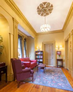 a living room with a red couch and a chandelier at Chipman Hill Suites -Yeats House in Saint John