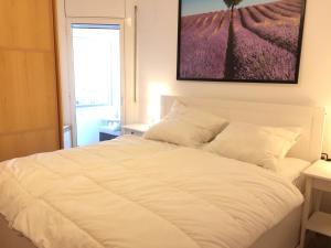 ein weißes Bett in einem Schlafzimmer mit einem Bild an der Wand in der Unterkunft BarcelonaVacances-Katrin in Arenys de Mar