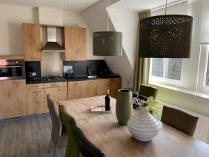 une cuisine avec une table en bois et un vase. dans l'établissement De Eerste Stuiver, à Hollum