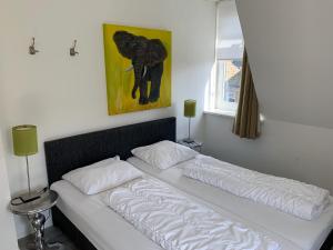 ein Bett in einem Schlafzimmer mit einem Bild eines Elefanten in der Unterkunft De Eerste Stuiver in Hollum