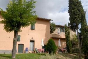a house with chairs and umbrellas in front of it at room in farmhouse near san gimignano in San Gimignano