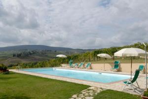 a swimming pool with lawn chairs and umbrellas at room in farmhouse near san gimignano in San Gimignano