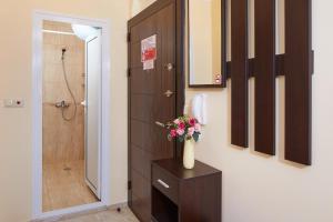 a bathroom with a shower and a vase of flowers on a table at Feniks Apartments in Nesebar +78 photos