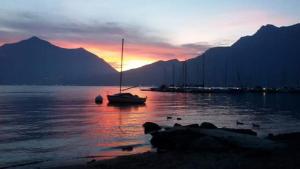 um barco sentado na água com um pôr-do-sol ao fundo em Il porticciolo em Bellano