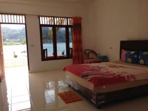 a bedroom with a bed and a view of the water at Aman's Guesthouse in Tuktuk Siadong