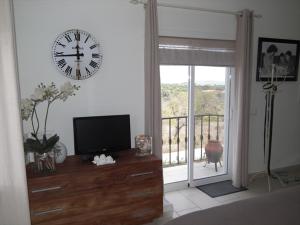 ein Wohnzimmer mit einer Uhr an der Wand und einem TV in der Unterkunft Casa Marinha Beach in Lagoa