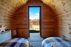 two beds in a room with a large window at Howe of Torbeg in Ballater