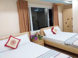 two beds in a room with a window at Thanh Trung Hotel in Cat Ba