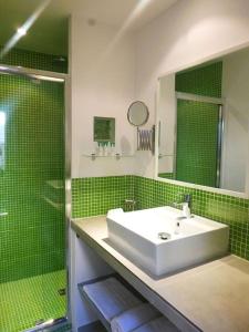 een groene betegelde badkamer met een wastafel en een douche bij La Maison du Courtil, Pistache-Chocolat in Moustiers-Sainte-Marie