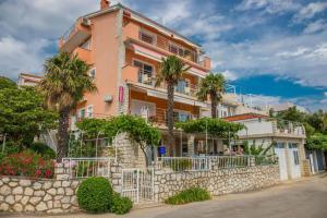 ein rosa Gebäude mit Palmen davor in der Unterkunft Apartments Zorica in Dramalj