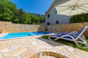 uma piscina com cadeiras e um guarda-sol ao lado de uma piscina em Apartment LINDA em Grižane