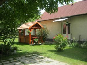 a house with a wooden gazebo in the yard at Csikász Vendégház in Nagyvisnyó