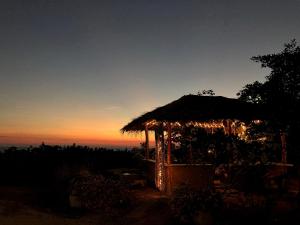 a hut with a thatched roof at sunset at The Horizon Hill Top Villa in Unawatuna