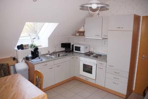 d'une cuisine avec des placards blancs, un évier et une fenêtre. dans l'établissement Ferienwohnung im Hainertal, à Heigenbrücken