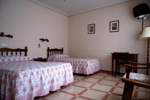 1 dormitorio con 2 camas, mesa y sillas en Hostal San Poul, en Consuegra